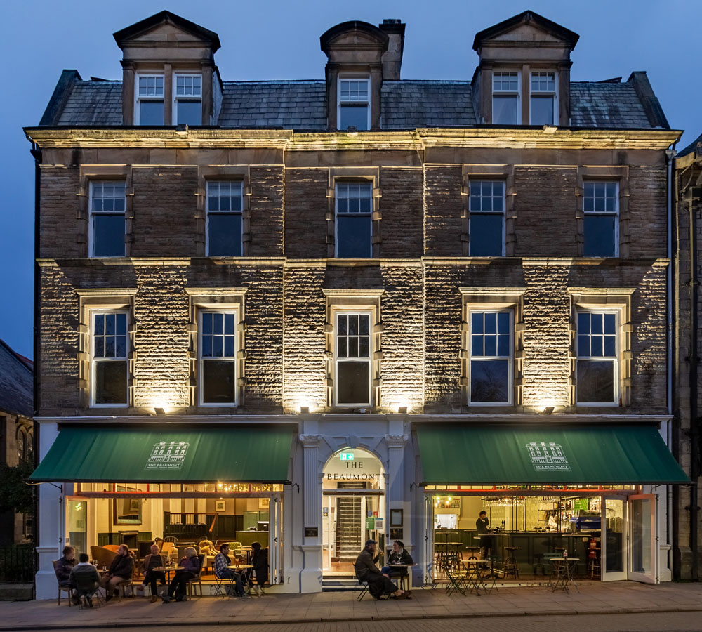 alt="Dining out image of The Beaumont Hotel in Hexham lit up in the evening"