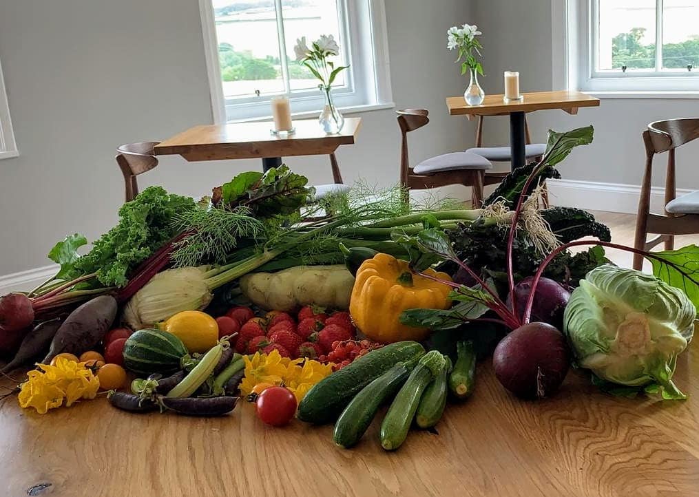 alt="locally grown fruit and veg on a dining table"