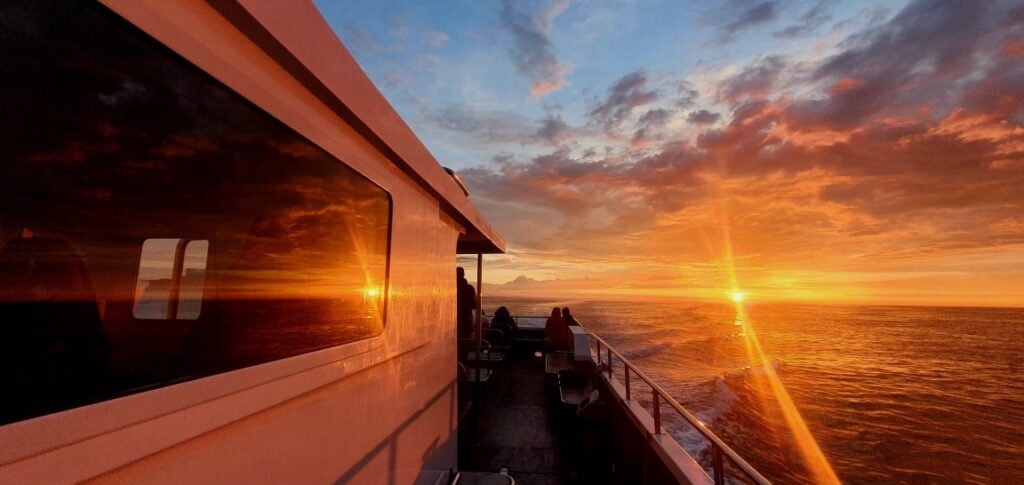 alt="Sunset cruise with sun low in the sky over the sea"